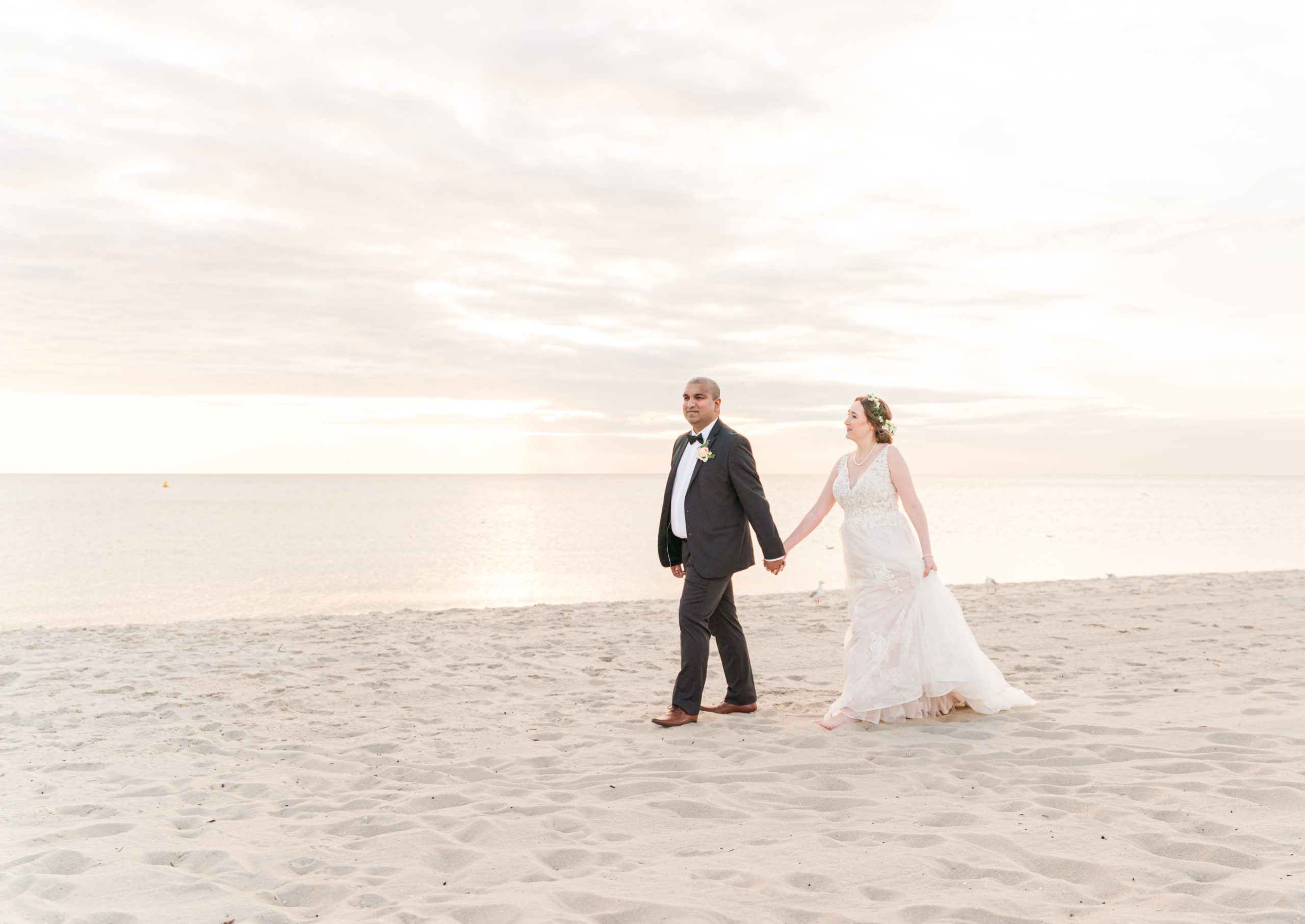 Newly married couple walking on Chelsea beach at sunset